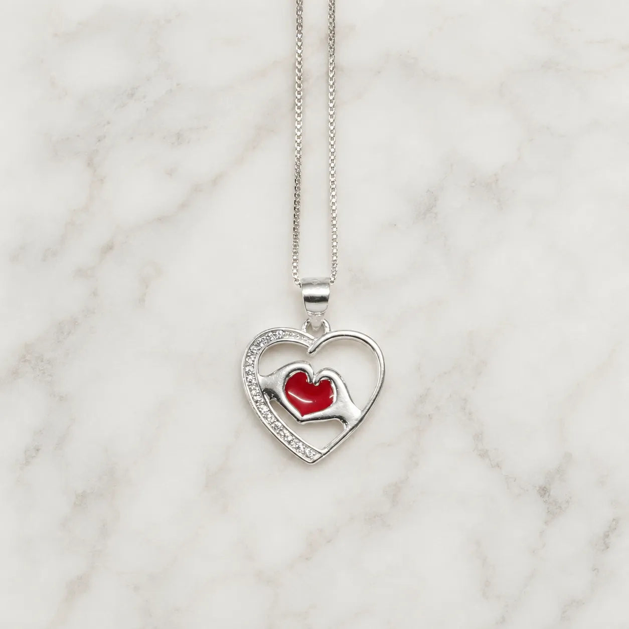 Collar corazón con manos y corazón rojo